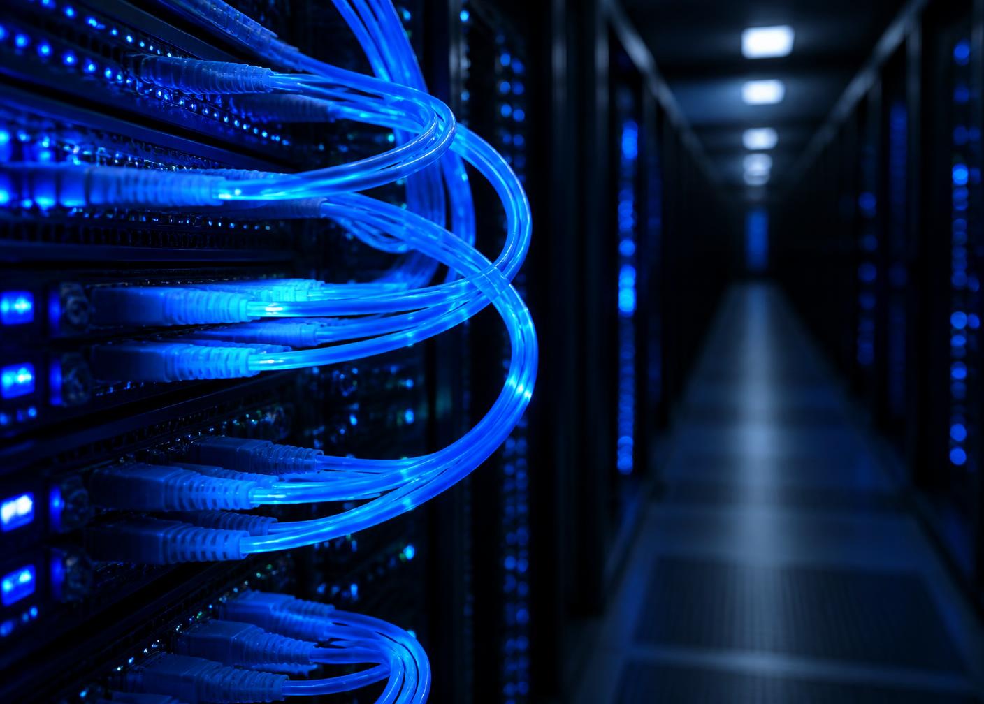 Blue fibre optic cabling in a dark data centre aisle